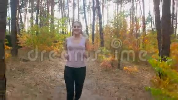 4K镜头年轻的微笑的女人在森林里享受跑步视频的预览图