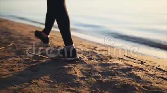 近距离拍摄穿黑色运动鞋的女人腿在沙滩上行走视频的预览图