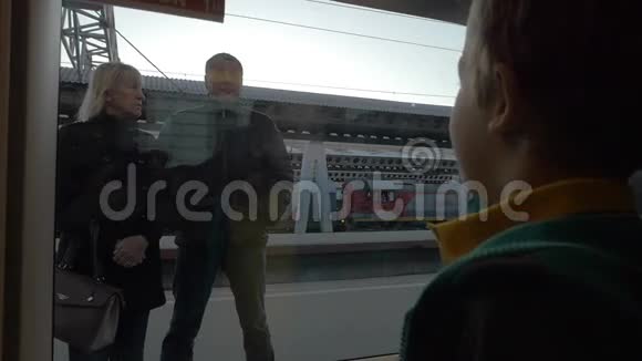 在圣彼得堡慢动作俄罗斯小男孩从火车窗口向站在火车上的祖父母挥手视频的预览图