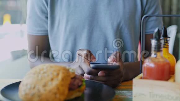在自助餐厅的午餐时间关闭在智能手机上发短信的面目全非的黑人视频的预览图