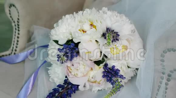 豪华照相馆白色扶手椅上的婚礼花束一束紫色丝带的牡丹和羽扇豆视频的预览图