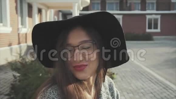 在户外戴着黑色帽子和眼镜的漂亮微笑的女人的肖像视频的预览图