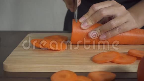 慢动作关闭妇女制作健康食品和切胡萝卜在厨房的砧板上视频的预览图