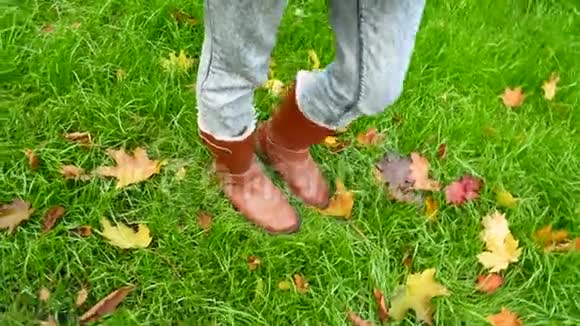 穿靴子的雌腿在绿草和落叶的背景下视频的预览图