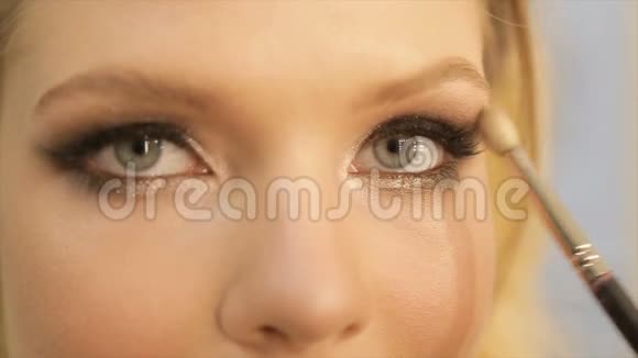 化妆师将明亮的基本彩色眼影涂在女孩的眼睛上视频的预览图
