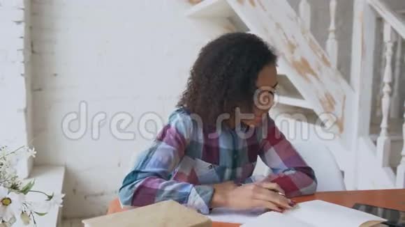 年轻的卷发混血女孩坐在桌子旁集中精力学习考试视频的预览图