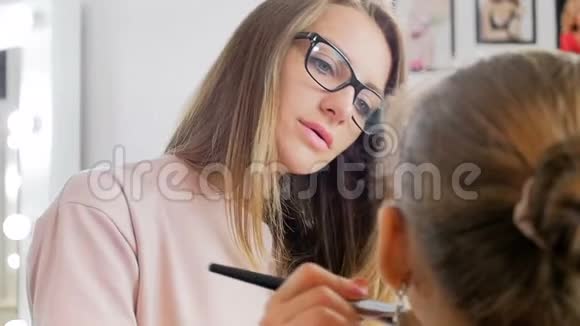 专业化妆师应用化妆品及准备年轻女性模特的特写慢镜头视频视频的预览图