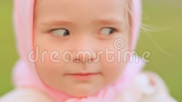 在镜头前摆姿势的俄罗斯小女孩微笑近距离的看着头上是粉红色的头巾视频的预览图