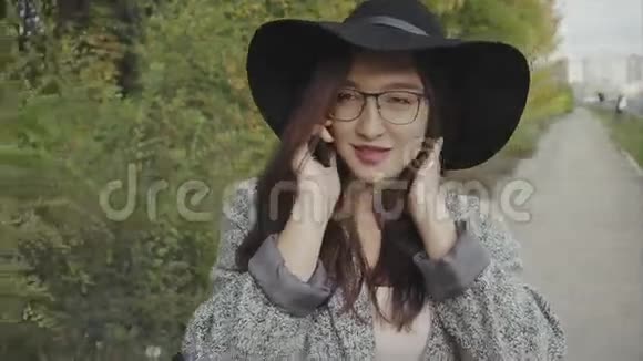 戴着黑帽子戴着眼镜的年轻漂亮女人在户外给她的朋友打电话视频的预览图