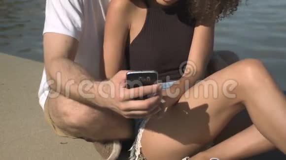 快乐的年轻夫妇在阳光公园用手机看照片视频的预览图