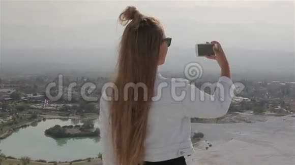 一位美国旅行者在一个历史遗址上拍摄一张照片帕姆卡莱用一部智能手机站在山上视频的预览图