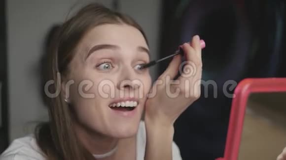 美丽的少女心情愉快化妆画睫毛睫毛膏对着镜子欣赏自己视频的预览图