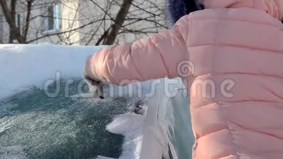 一个年轻女人从车里擦雪的冬天画像美女金发模特女孩笑着兴高采烈地打扫卫生视频的预览图