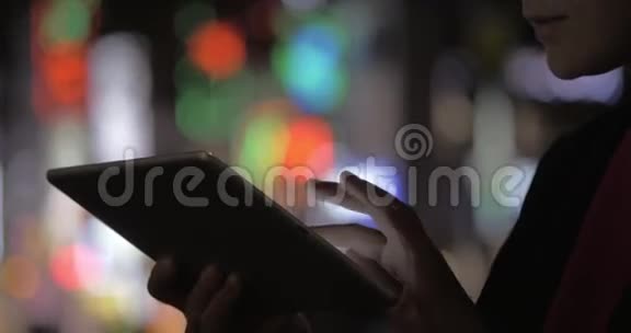 夜晚女人用垫垫在五颜六色模糊的城市灯光上视频的预览图