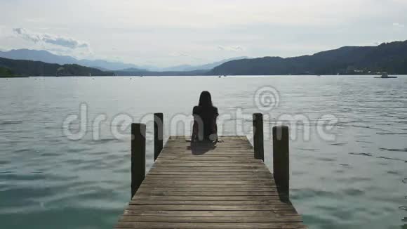 在山湖放松女人坐在码头上视频的预览图