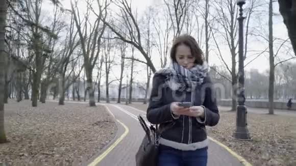 带着智能手机在城市公园散步的女人视频的预览图