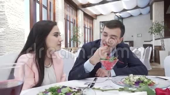 一对情侣在餐厅晚餐时一个男人在一段吻盘视频中用浆果喂一个女孩视频的预览图
