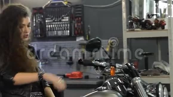 女摩托车手在摩托车车间动头发视频的预览图