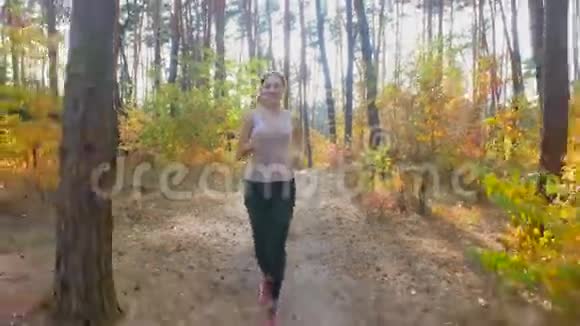 4K镜头年轻的微笑的女人在森林里享受跑步视频的预览图