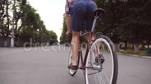 年轻人在公园路上骑着一辆老式自行车运动的家伙在户外骑自行车健康的积极生活方式低角度视频的预览图