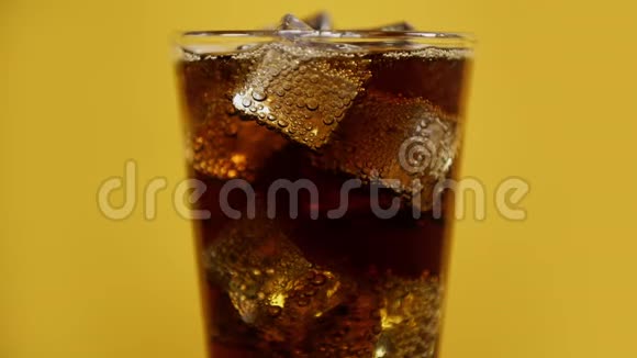 可乐泡沫饮料与冰块玻璃冷可乐闪烁苏打黄色背景视频的预览图
