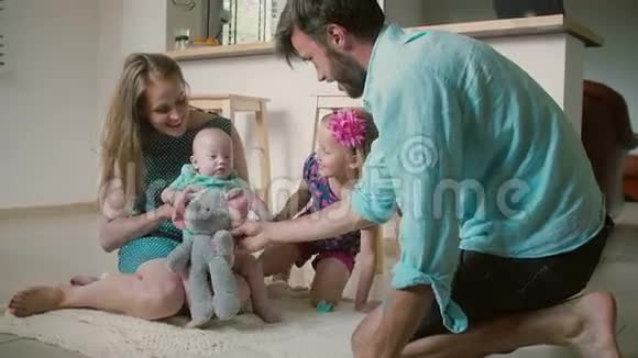 年轻漂亮的家庭正在厨房地板上和最小的婴儿儿子玩耍慢动作视频的预览图