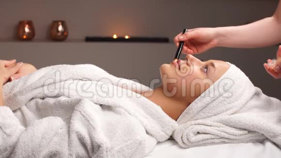 美容师将面膜敷在水疗沙龙的年轻女性脸上视频的预览图