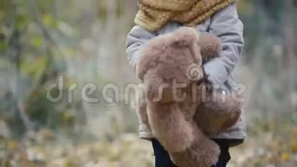 快乐的金发小女孩在秋天公园玩玩具熊视频的预览图