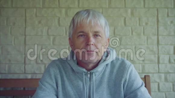 坐在长凳上的房子外老人白发苍苍的画像视频的预览图