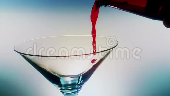 在蓝光色调背景下倒入带有冰块的红色新鲜酒精鸡尾酒酒杯拍摄慢动作有趣和舞蹈迪斯科视频的预览图