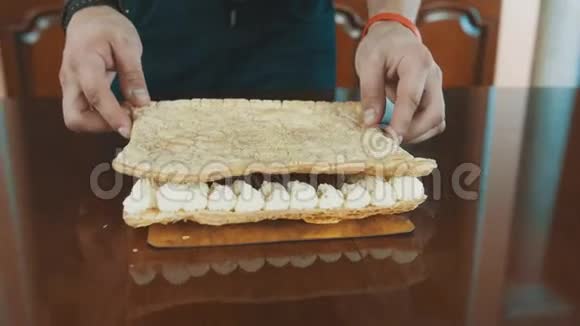 糖果男手把蛋糕层放在加鞭的奶油上视频的预览图