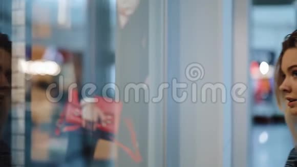迷人的金发女郎站在商场的橱窗前视频的预览图