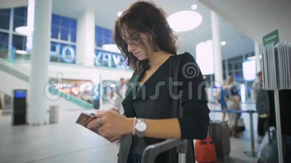 一位年轻的女士正在考虑拿着智能手机旅行视频的预览图