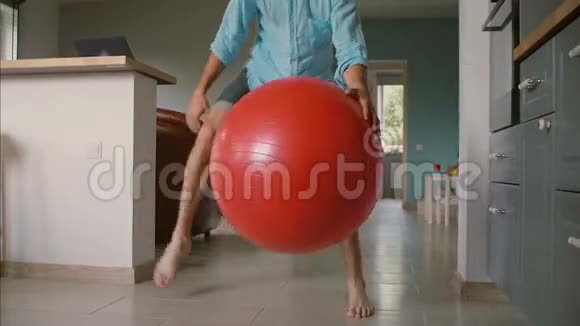年轻的父亲正在和他的小女儿一起打篮球客厅里有一个大红色的健身房气球慢动作视频的预览图