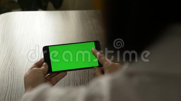 女人拿着一部绿色屏幕的手机供你的视频内容视频的预览图