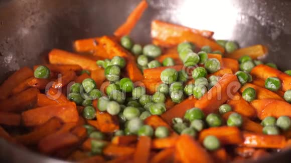 豌豆和胡萝卜在锅里炒煎锅里的蔬菜在金属煎锅里放油蔬菜视频的预览图
