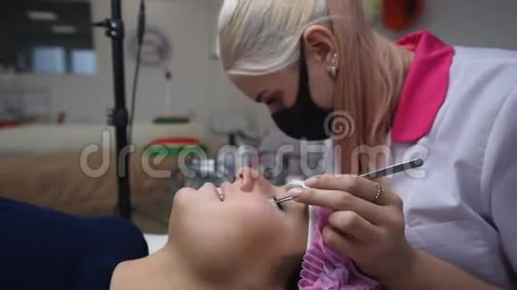 专业美容师进行睫毛延伸手术现代美容院的老板和客户视频的预览图