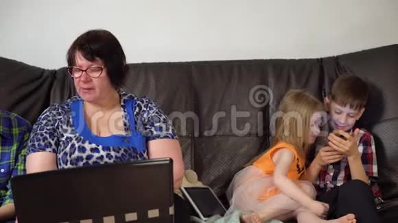 一家人坐在沙发上使用数字设备视频的预览图