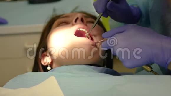 牙医检查年轻女孩的口腔用嘴唇推动仪器4k3840x2160视频的预览图