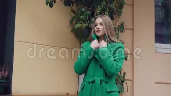 穿绿色外套摆姿势对着4K相机的时髦女孩视频的预览图