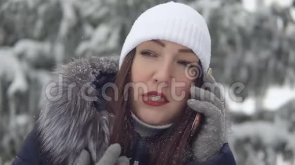 一位在冬季公园打电话的年轻女子视频的预览图
