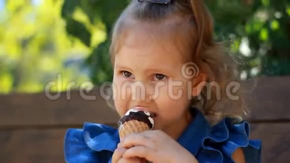 小女孩在阳光明媚的夏天在公园里吃冰淇淋和巧克力婴儿特写的肖像视频的预览图