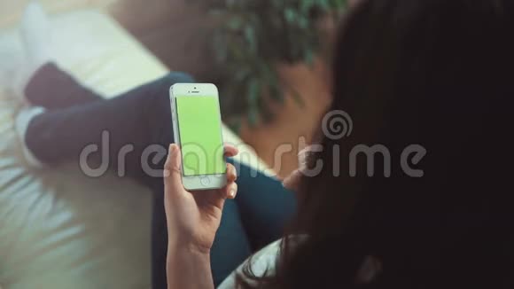 女人坐在白色沙发上用智能手机视频的预览图