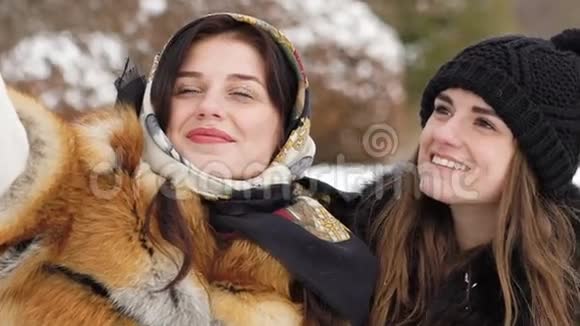 两个年轻女孩在冬季公园自拍慢动作视频的预览图