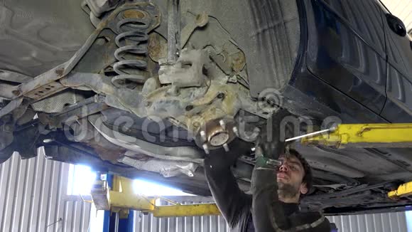熟练的机械师在汽车下面的车库中拆卸磨损的汽车部件视频的预览图