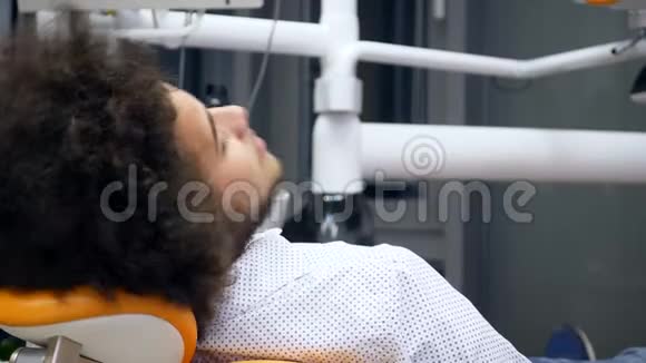 一个年轻英俊的男人坐在牙医的椅子上他转过身来微笑成相机视频的预览图