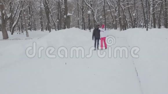 男孩和女孩走在白雪覆盖的公园里视频的预览图