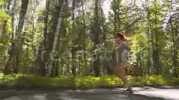 一个红头发的女孩在森林里跑步户外训练的漂亮女运动员慢动作视频的预览图