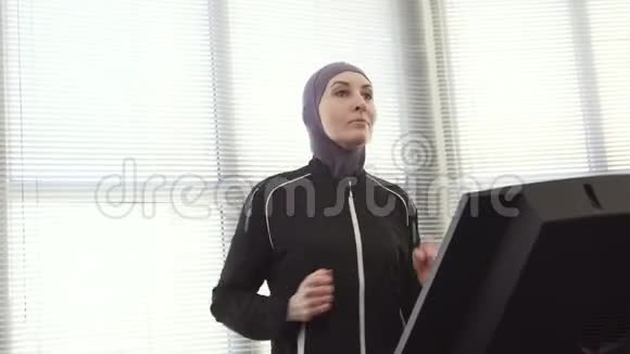 戴着头巾的女运动员在跑步模拟器上视频的预览图