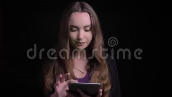 用平板电脑拍摄白种人年轻漂亮的黑发女性的特写镜头并用绿色屏幕拍摄视频的预览图